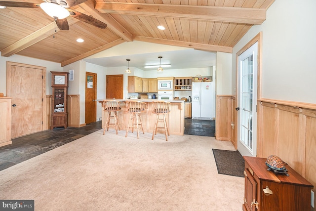 kitchen featuring wooden ceiling, white appliances, wainscoting, light countertops, and a kitchen bar