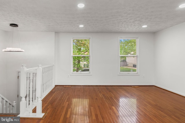 empty room featuring wood-type flooring, a textured ceiling, baseboards, and recessed lighting