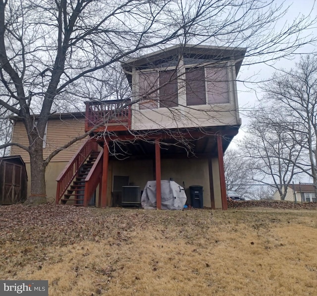 exterior space with an outbuilding, a wooden deck, a storage unit, stairs, and stucco siding