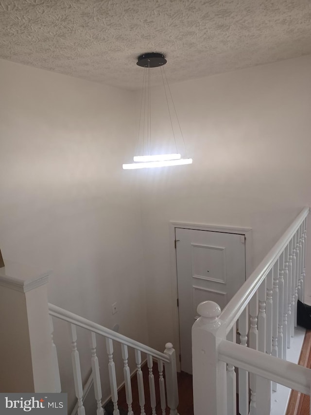 stairs featuring a textured ceiling