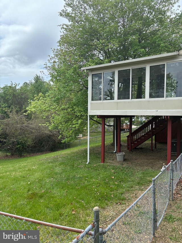 view of yard featuring fence, a sunroom, and stairway