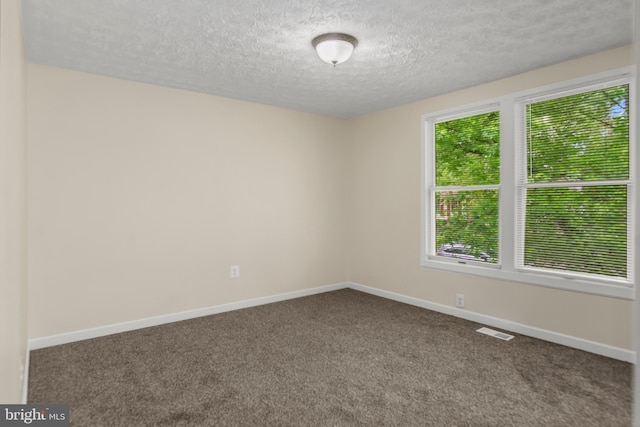 carpeted empty room with visible vents, a textured ceiling, and baseboards