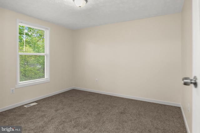 carpeted spare room with visible vents and baseboards