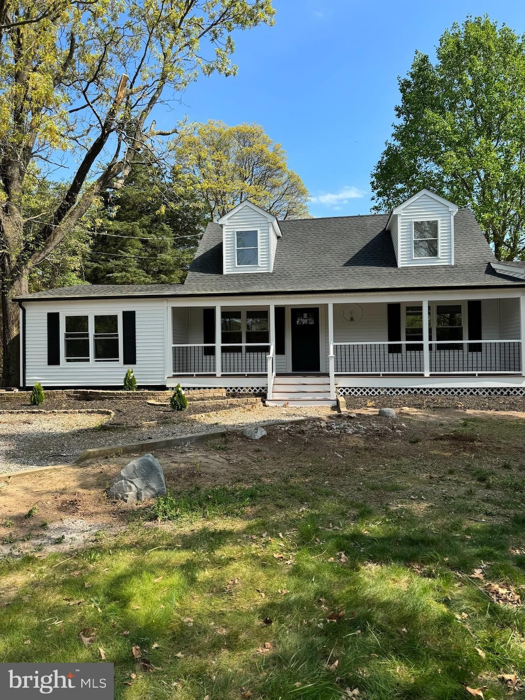 cape cod house featuring a porch, a shingled roof, and a front lawn