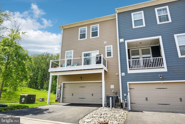 1579 Meadowlark Glen Rd, Dumfries, VA 22026 - rear view of house featuring an attached garage, central AC unit, aphalt driveway, and a balcony
