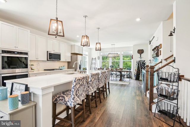 1579 Meadowlark Glen Rd, Dumfries, VA 22026 - kitchen with dark wood-style flooring, appliances with stainless steel finishes, a sink, decorative backsplash, and a center island with sink