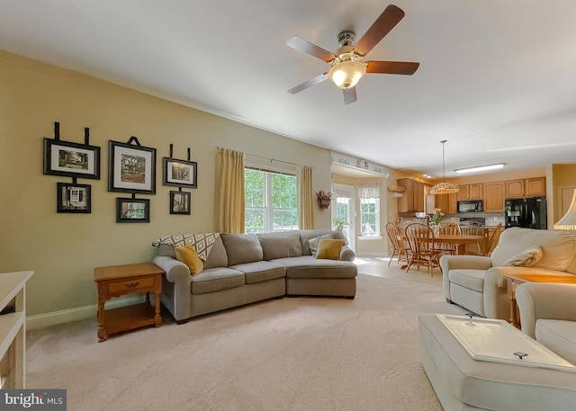 living room with baseboards, a ceiling fan, and light colored carpet