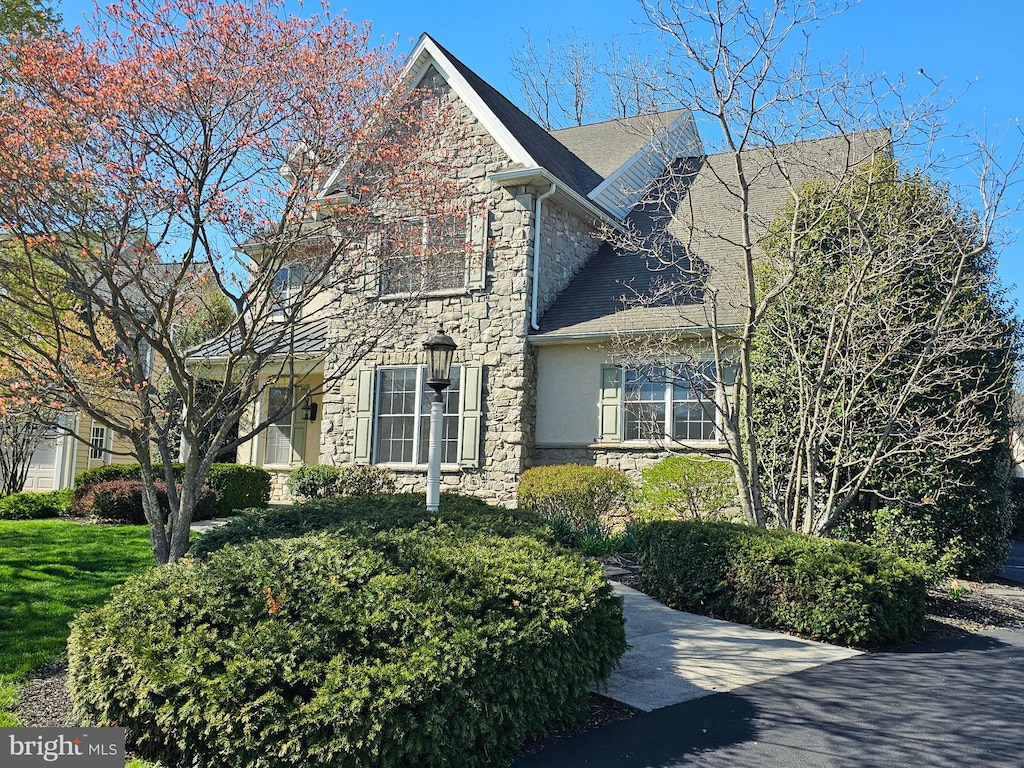 view of home's exterior with a shingled roof and stone siding