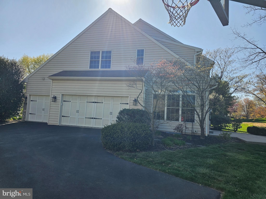 view of front of property featuring aphalt driveway, a front yard, and an attached garage