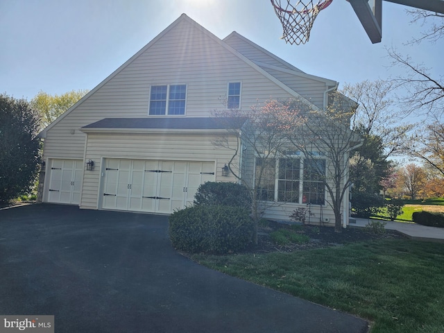 view of front of property featuring aphalt driveway, a front yard, and an attached garage