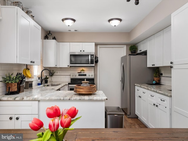 kitchen featuring a sink, appliances with stainless steel finishes, white cabinetry, and visible vents