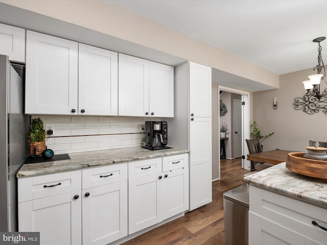 kitchen featuring decorative backsplash, decorative light fixtures, wood finished floors, white cabinets, and an inviting chandelier