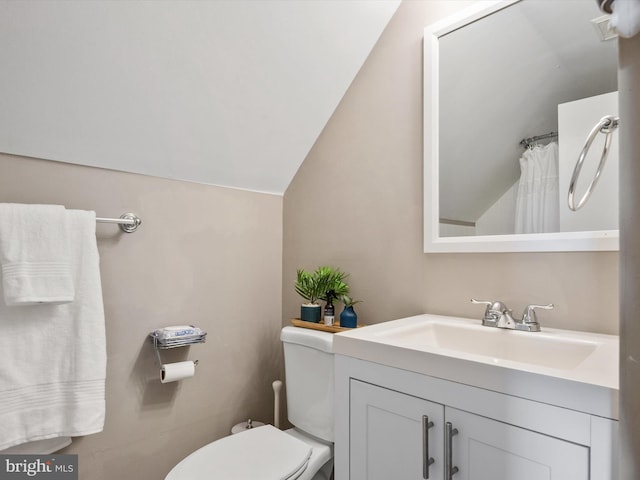 bathroom featuring vanity, vaulted ceiling, and toilet