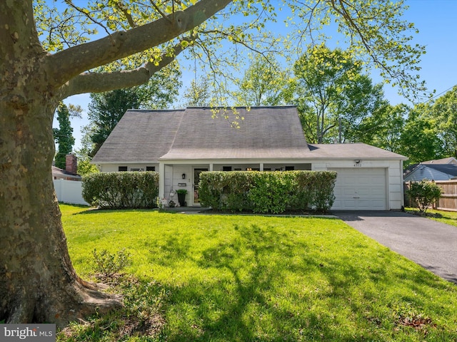 view of front facade featuring a garage, a front lawn, fence, and driveway