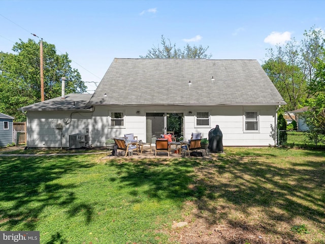 rear view of property with fence, cooling unit, roof with shingles, a patio area, and a lawn