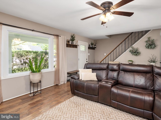 living area featuring baseboards, a ceiling fan, stairs, and wood finished floors