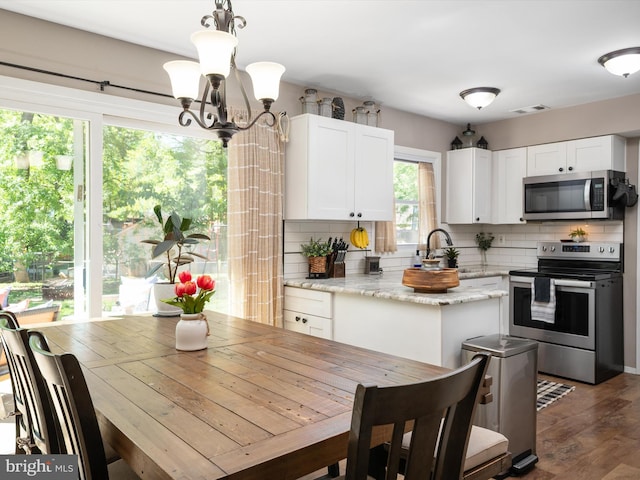 kitchen featuring visible vents, an inviting chandelier, white cabinetry, backsplash, and stainless steel appliances