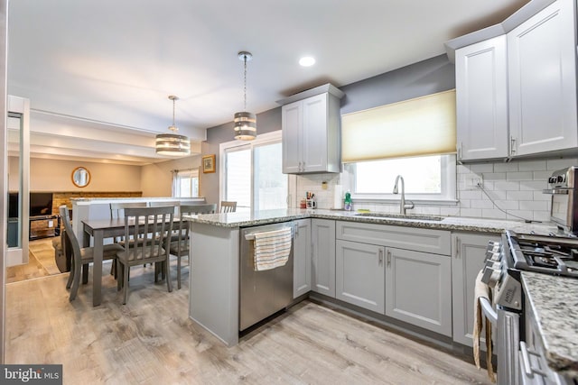 kitchen featuring a sink, backsplash, stainless steel appliances, and light wood-style flooring