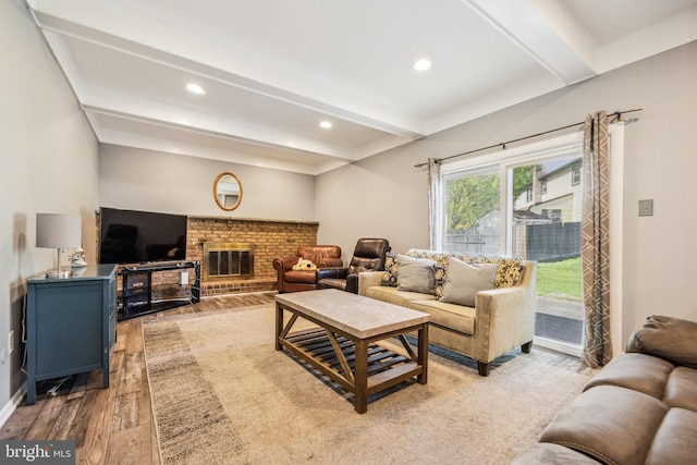 living room featuring a brick fireplace, beam ceiling, baseboards, light wood finished floors, and recessed lighting