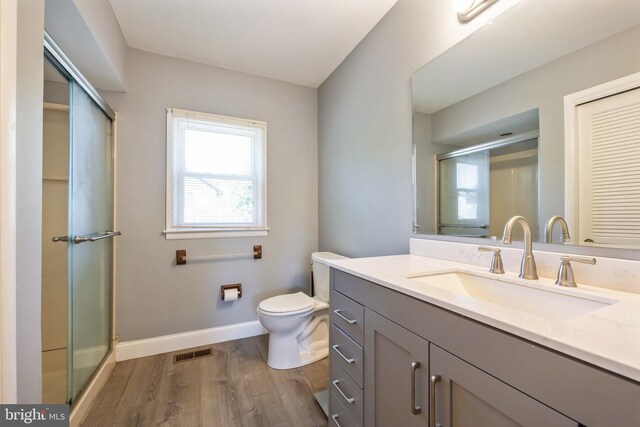 bathroom with baseboards, visible vents, wood finished floors, and a stall shower