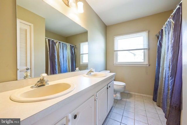 bathroom with double vanity, a sink, tile patterned flooring, and toilet