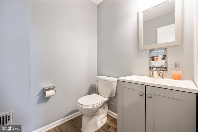 half bathroom featuring toilet, baseboards, wood finished floors, and vanity
