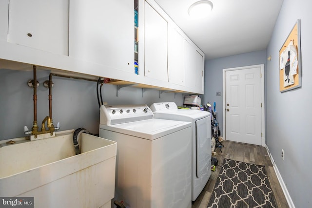clothes washing area with baseboards, dark wood finished floors, a sink, cabinet space, and independent washer and dryer
