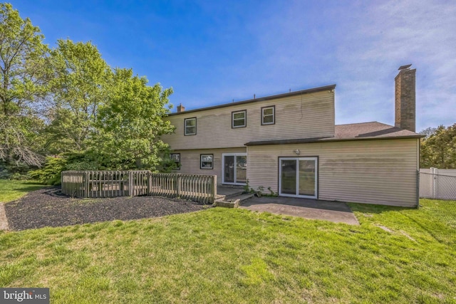 rear view of house featuring a lawn, fence, a patio, and a chimney