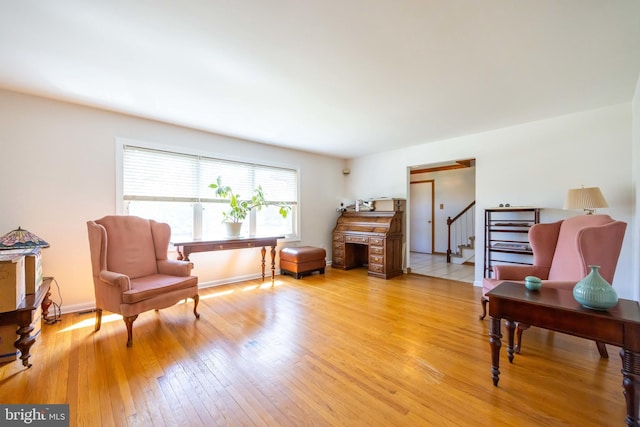 living area featuring stairs, baseboards, and light wood-style floors