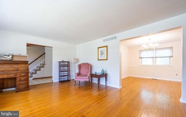 living area featuring an inviting chandelier, light wood-style floors, stairs, baseboards, and visible vents