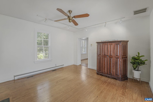 unfurnished room with track lighting, a baseboard heating unit, a ceiling fan, light wood-type flooring, and baseboards