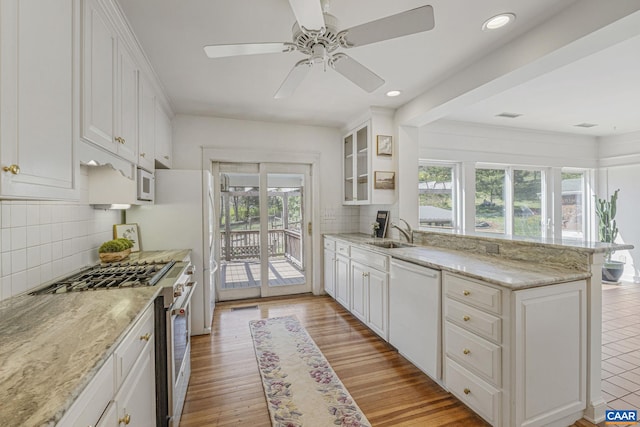 kitchen featuring white appliances, a sink, a peninsula, white cabinetry, and recessed lighting