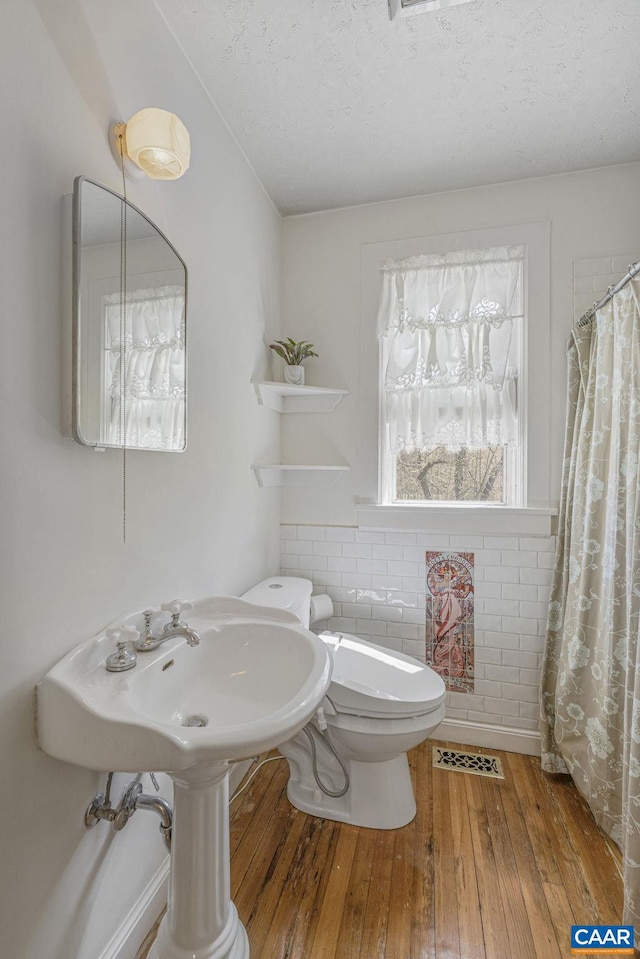 bathroom with hardwood / wood-style flooring, a textured ceiling, toilet, and a shower with curtain