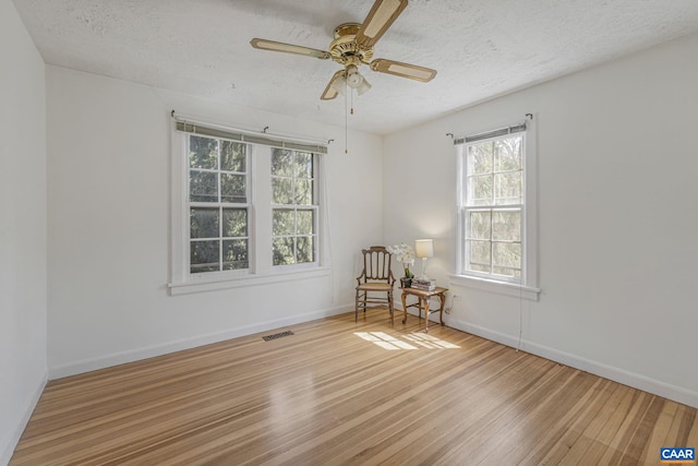 unfurnished room featuring hardwood / wood-style floors, a textured ceiling, ceiling fan, and baseboards