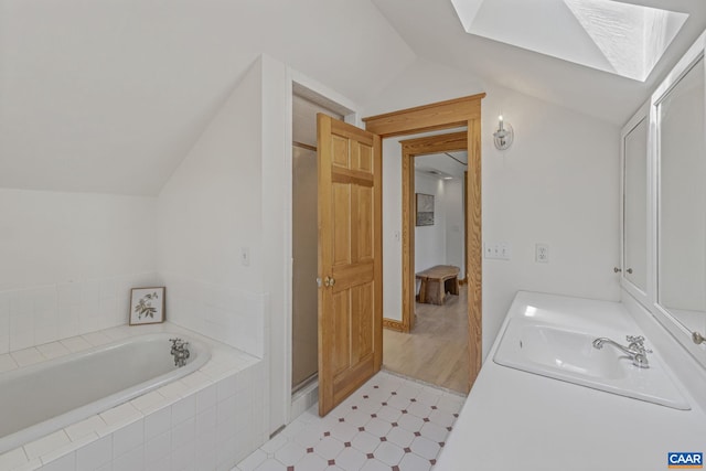 bathroom with vaulted ceiling, a bath, tile patterned floors, vanity, and a skylight