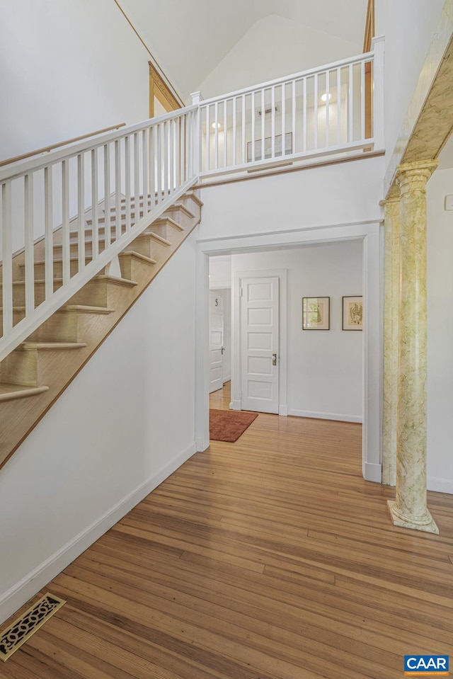 staircase featuring high vaulted ceiling, wood finished floors, and baseboards