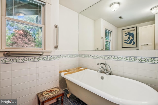 full bathroom with a soaking tub, tile walls, tile patterned floors, visible vents, and wainscoting