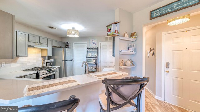 17 Bayside Dr, Somers Point, NJ 08244 - kitchen with visible vents, decorative backsplash, light wood-style floors, under cabinet range hood, and appliances with stainless steel finishes