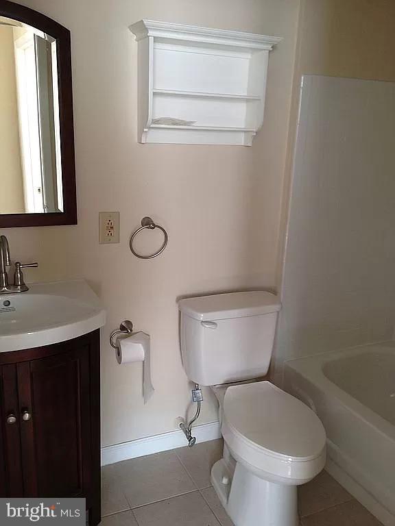 bathroom with vanity, toilet, tile patterned flooring, and baseboards