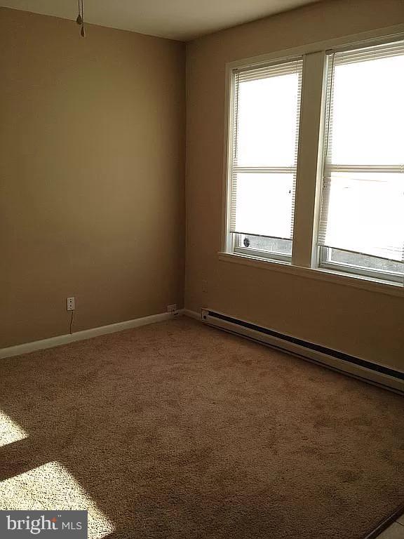 unfurnished room featuring baseboard heating, baseboards, and carpet