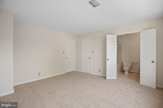 unfurnished bedroom featuring carpet floors, baseboards, visible vents, and ensuite bathroom