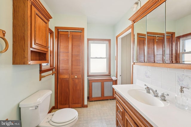 bathroom with a closet, vanity, toilet, tile patterned floors, and tasteful backsplash