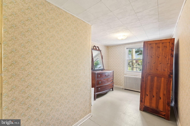 bedroom with wallpapered walls, baseboards, and radiator