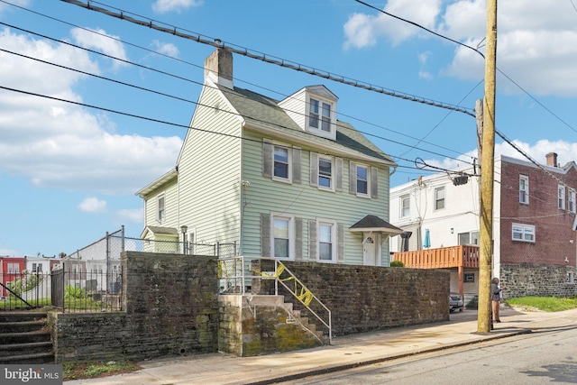 view of front of home with fence, a chimney, and stairway
