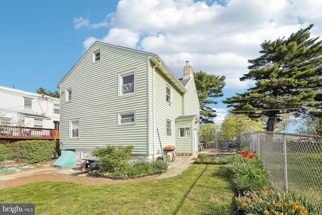 rear view of property featuring a lawn, fence, and a chimney