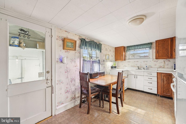 dining area with light floors, wallpapered walls, and a wealth of natural light