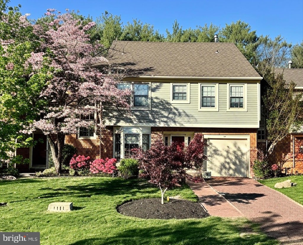 colonial-style house with a front yard, concrete driveway, a garage, and brick siding