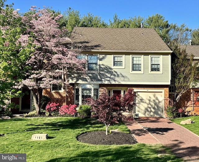 colonial-style house with a front yard, concrete driveway, a garage, and brick siding