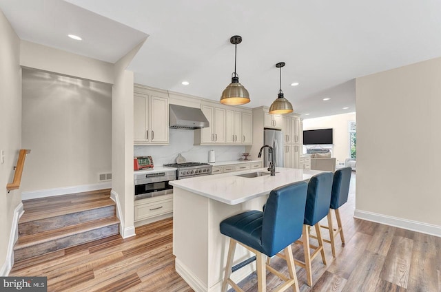 20 Wolfpack Rd, Hamilton, NJ 08619 - kitchen featuring a breakfast bar area, wall chimney range hood, light countertops, a sink, and appliances with stainless steel finishes