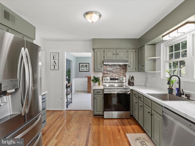 214 Primavera Cir, Sterling, VA 20165 - kitchen featuring light countertops, under cabinet range hood, a sink, light wood-style flooring, and stainless steel appliances